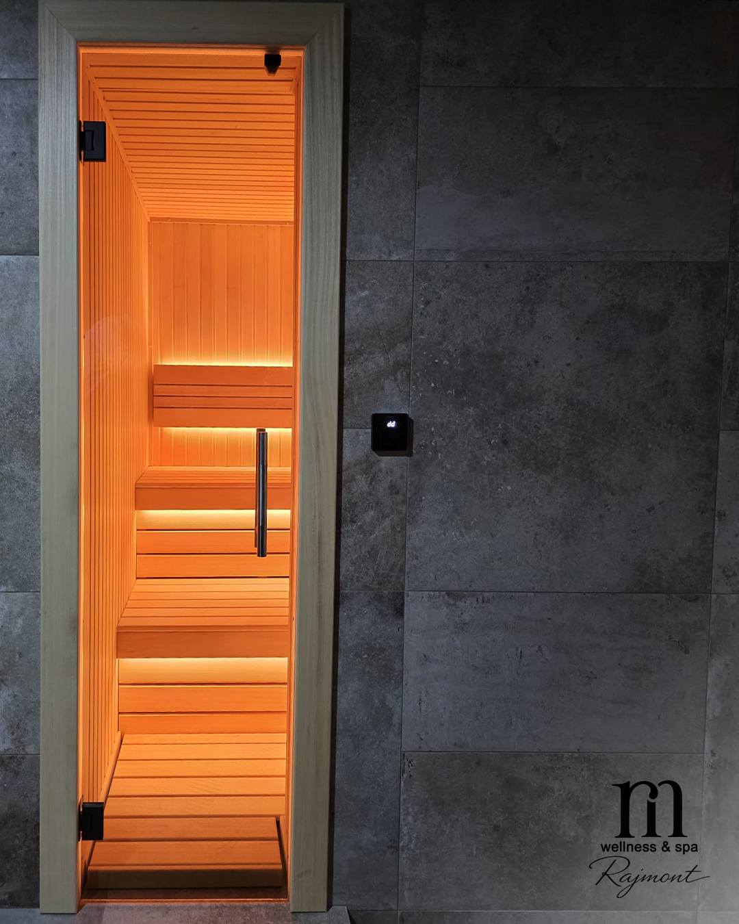 Kompaktna kućna sauna po meri dimenzija 200x180 cm sa staklenim vratima, svetlim drvenim enterijerom i toplim narandžastim LED osvetljenjem integrisanim u tamni zid kupatila.